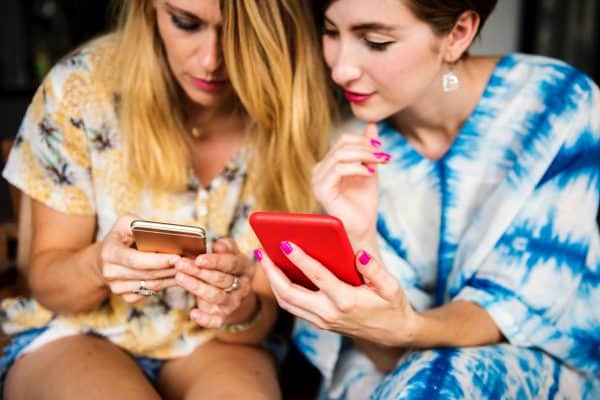 two women share videos on their smartphones