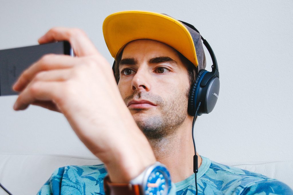 man watches video on cell phone while using headphones