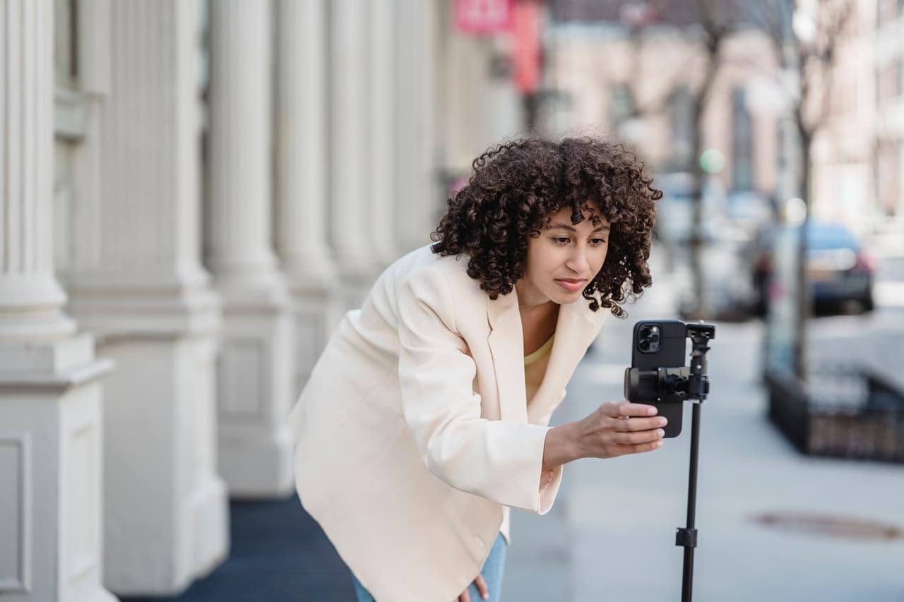 woman adjusting cell phone on tall tripod for vertical video recording
