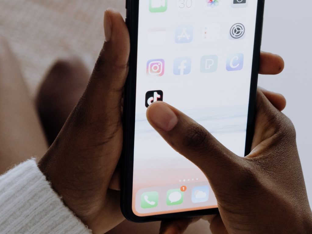 african-american woman's hands holding mobile phone with the TikTok app highlighted