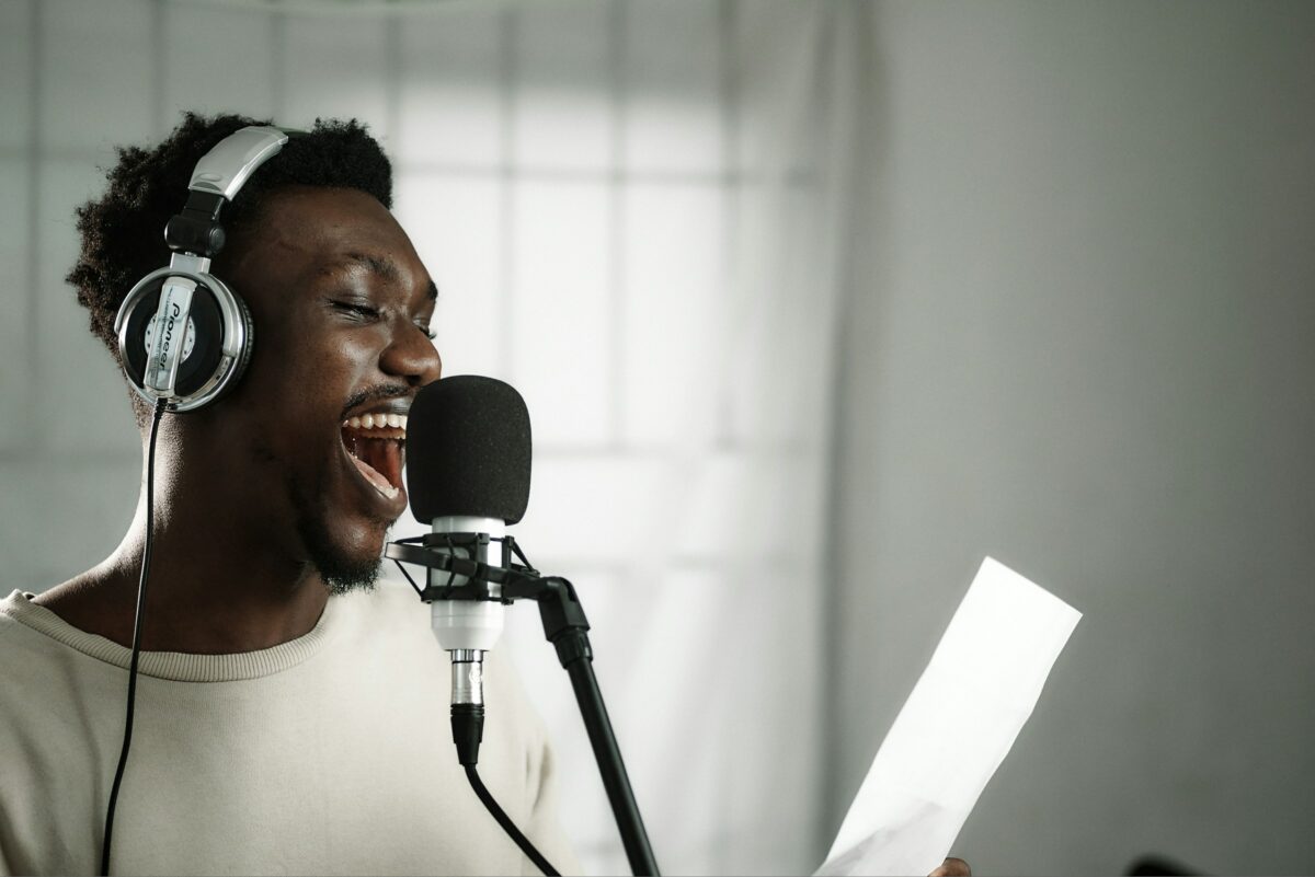 a black, male video spokesperson records an animated scene into a microphone while holding a script.