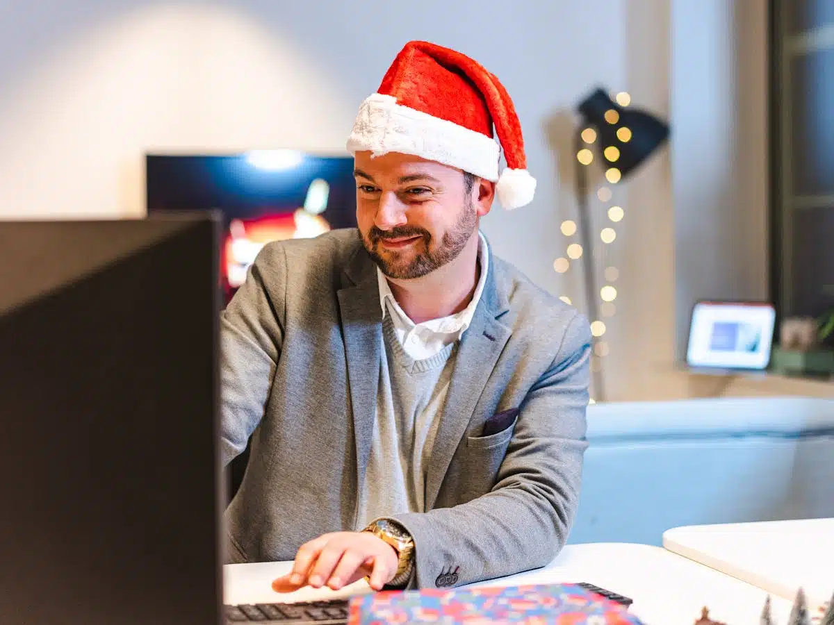 a white male with a neatly trimmed beard wears a Santa hat while watching a corporate Christmas video